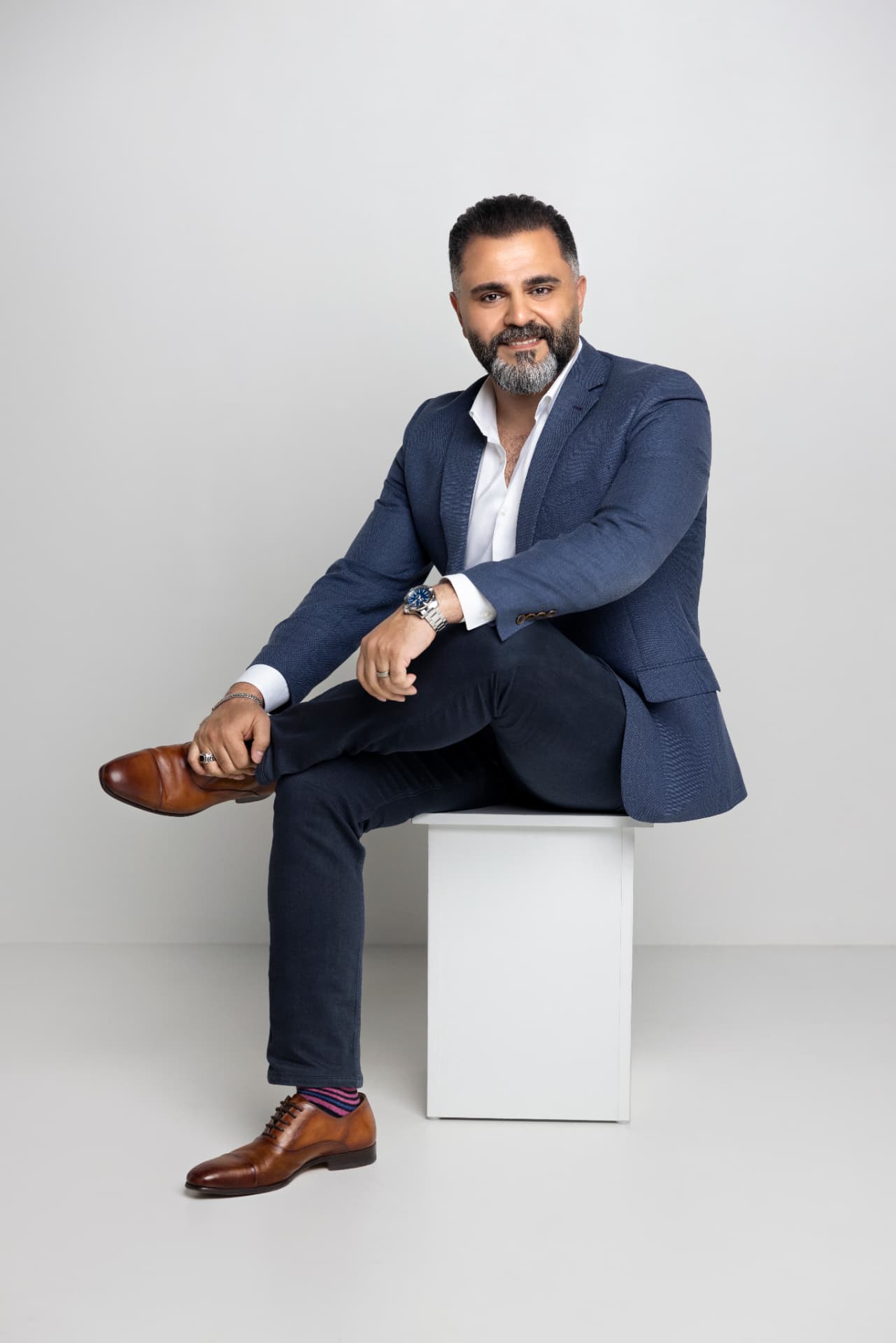 Alaa Hassan seated, wearing a blue jacket, during a portrait session
