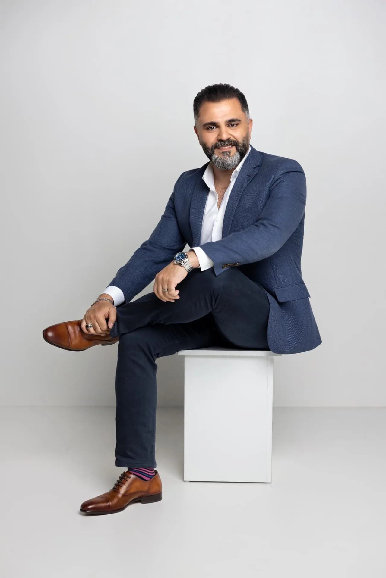 Alaa Hassan seated, wearing a blue jacket, during a portrait session